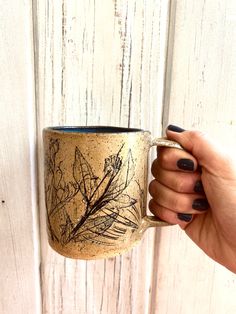 a hand holding a coffee cup with designs on it, in front of a white door