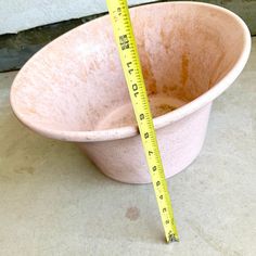 a pink bowl with a measuring tape in it