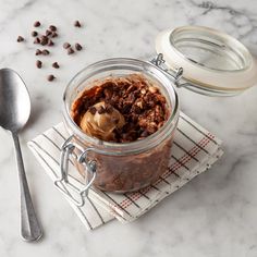 a glass jar filled with food sitting on top of a table next to a spoon