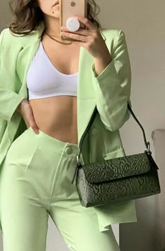 a woman taking a selfie with her cell phone and green pants in the foreground