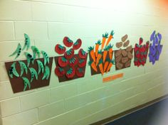 some paper flowers and carrots on a wall in a school hallway or classroom room