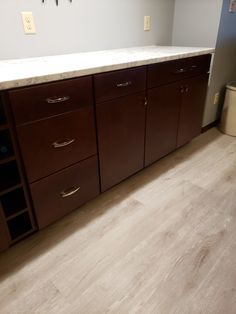 an empty kitchen with brown cabinets and white counter tops in the middle of the room