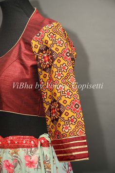 This Maroon blouse is hand-painted on raw silk and embellished with embroidery and Patola sleeves design. It provides a versatile style, perfect for mixing and matching with multiple sarees. Its 3/4th sleeves give this blouse a modern, sophisticated silhouette and style to your wardrobe this festive season. Traditional Long Sleeve Saree For Festivals, Brown Traditional Wear With Motifs For Festive Occasions, Festive Brown Traditional Wear With Motifs, Traditional Brown Blouse Piece For Festive Occasions, Long Sleeve Blouse With Traditional Patterns For Festivals, Traditional Brown Blouse For Festive Occasions, Festive Long Sleeve Blouse With Traditional Patterns, Traditional Silk Tops With Motifs, Red Blouse With Traditional Patterns For Navratri