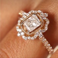 a woman's hand with an engagement ring and diamond halos on top of it