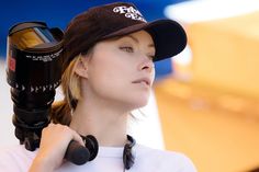 a woman is holding a camera on her shoulder and wearing a hat with the word'photographer'written on it