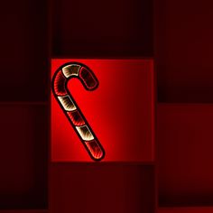 a candy cane lit up in the middle of a red wall with squares behind it