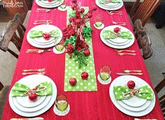 the table is set for christmas dinner with red and green decorations