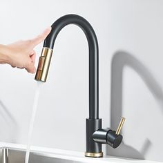 a person's hand is spouting water from a kitchen faucet