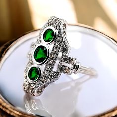 Discover the timeless elegance of our vintage 925 solid sterling silver rhodium plated vibrant simulated emerald ring, a true testament to exquisite craftsmanship and vintage charm. This stunning piece features three radiant simulated emerald and accented by sparkling cubic zirconia stones. Each ring is stamped with '925', ensuring the authenticity and premium quality of sterling silver, which guarantees both durability and a lasting shine. Perfect for any occasion, this ring effortlessly adds a touch of sophistication to your everyday wear or serves as a dazzling statement piece for special events. The vibrant sim emeralds capture the eye with their rich, green hues, while the delicate filigree design exudes an air of timeless elegance and intricate detail. Whether you're treating yoursel Exquisite Silver Emerald Ring, Green Hues, Anniversary Present, Rich Green, Filigree Design, Multi Stone Ring, Vintage Ring, Multi Stone, Emerald Ring