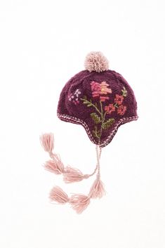 a knitted hat with flowers and tassels