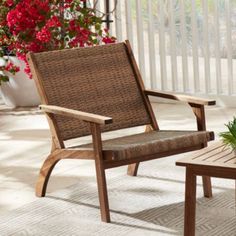 a wooden chair sitting on top of a patio next to a table with flowers in it