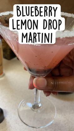 a hand holding a drink in a glass with the words blueberry lemon drop martini