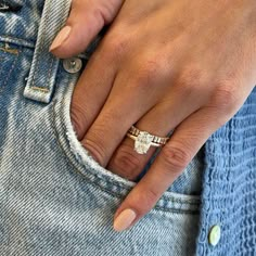 a close up of a person's hand with a ring on their finger, wearing jeans