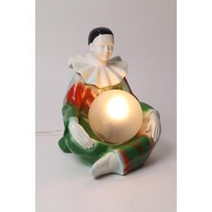 a ceramic figurine with a light in the shape of a person holding a ball