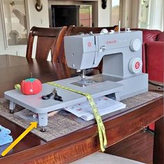 a sewing machine sitting on top of a wooden table next to a yellow tape measure