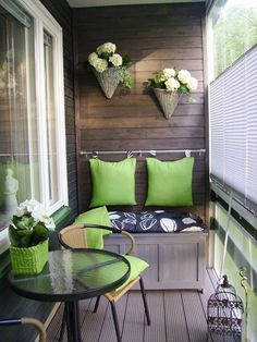 a small balcony with green pillows and white flowers