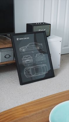 there is a framed drawing of a car on the floor in front of a tv