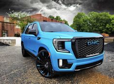 a blue truck parked in front of a building under a cloudy sky with black clouds