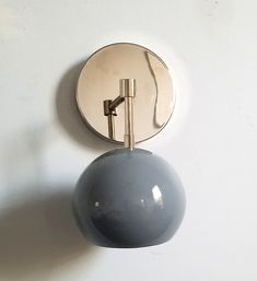 a round mirror mounted to the side of a white wall next to a gray ball