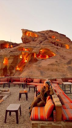 a woman sitting on top of a couch in front of a rock formation with lights