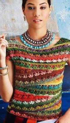 a woman wearing a multicolored crochet top and necklace with her hand on her hip