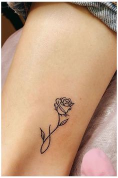 a small rose tattoo on the side of a woman's leg, it is black and white