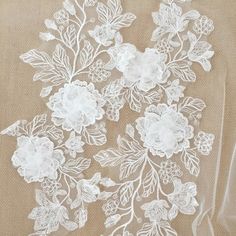 white lace flowers and leaves on a tan background with some fabric in the foreground