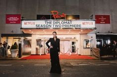 a woman standing in front of a movie theater with the marquee lit up