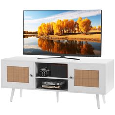 a flat screen tv sitting on top of a white entertainment center with wicker doors