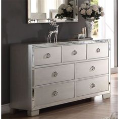 a white dresser with flowers and a mirror