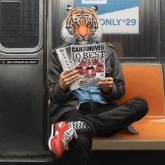 a tiger mask sitting on top of a subway car reading a newspaper with his eyes closed