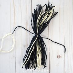 black and white yarn is laid out on a wooden surface with the string attached to it