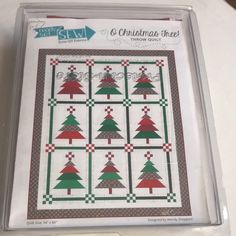 the christmas tree quilt pattern is on display in a clear box with white and red trimming