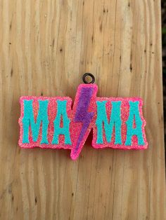 a pink and blue magnet with the word ma on it sitting on top of a wooden table