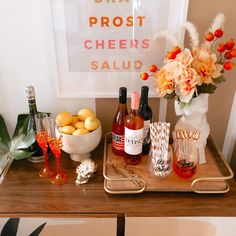 a table topped with bottles of wine and other alcohol next to a bowl of fruit