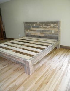 a bed frame made out of wood on top of a hard wood floor in an empty room