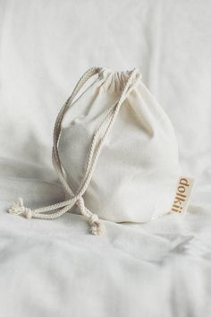 a white bag sitting on top of a bed covered in white sheets and pillows with the word dopp written on it