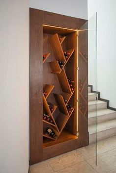 a wine rack in the corner of a room with stairs leading up to an open door