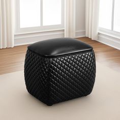 a black ottoman sitting on top of a white rug in front of a large window