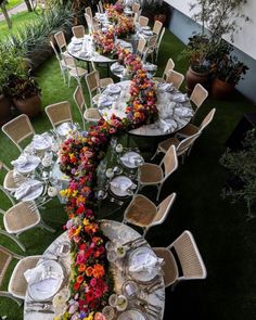 a long table is set up with flowers and place settings for an outdoor dinner party