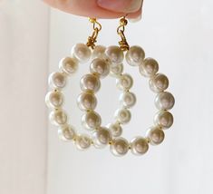 These beautiful oversized hoop pearl earrings are the ideal statement earrings for lovers of contemporary pearl jewellery and large dangle earrings. Vintage inspired 8mm white pearls sit upon golden wire, wrapped to a gold plated hook to create a beautiful dangle earring upgrade on classic hoop earrings. The perfect gift for pearl dangle earring fanatics. Minimalistic and geometric in style, the simplistic nature of the beads combined with the bold statement shape of the hoop create the perfect bold dangle earring for lovers of minimalist contemporary earrings with a unique bold twist. Modern White Pearl Earrings, Modern White Earrings With Pearl Charm, Modern White Round Pearl Earrings, Modern Pearl White Earrings With Pearl Charm, Modern Pearl Charm Earrings, Modern Pearl Earrings With Pearl Charm, Modern White Pearl Hoop Earrings, Modern White Single Pearl Earring, Gift Pearl White Hoop Earrings With Pearl Chain