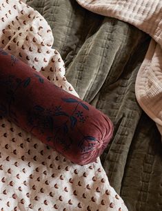 an unmade bed with two pillows on top of it and a red pillow in the middle