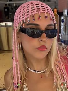 a woman with long blonde hair wearing sunglasses and a pink headdress is looking at the camera