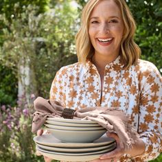 a smiling woman holding several plates in her hands