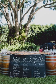 a wooden barrel filled with wine glasses on top of a grass covered field next to a tree