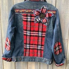 a red plaid jacket with a flower on the back, hanging up against a wooden wall