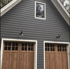 two brown garage doors are open in front of a gray house with white trim and windows