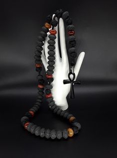 The Ankh Paracord Rosary is a unique 5 Decade Catholic Rosary that is based on the foundation of of Volcanic Lava stone that is directly extracted from Mt Vesuvius (all stones have been purified and cleansed). On top of that, it is supported by Carnelian beads and a black stainless steel Ankh Cross symbolizing the eternal life. Moreover, the rosary has been officially blessed by the church. If you are looking for a rosary that differentiates itself from the rest, the Ankh Paracord Rosary is the Black Beaded Necklace With Gemstone Beads, Black Gemstone Beaded Necklaces, Unique Black Beaded Necklaces With Gemstone Beads, Unique Black Gemstone Beaded Necklaces, Handmade Black Onyx Beaded Necklaces, Black Round Beads Jewelry For Rituals, Black Hand-strung Beads As Gift, Black Hand-strung Beads Gift, Gift Hand-strung Black Beads