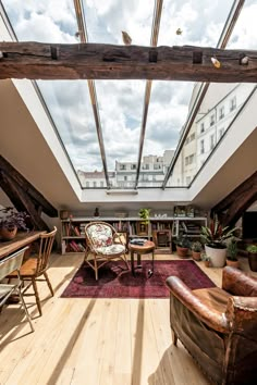 an attic living room with wooden floors and skylights above the couches, tables and chairs