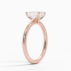 Emerald Cut Petite Elodie Solitaire Engagement Ring - 14K Rose Gold. This elegant solitaire ring features an open basket with claw prongs that cradle the center gem. The petite band adds to the sleek, classic look of the design. Rose Gold Moissanite Ring With Prong Setting, 14k Rose Gold Diamond Ring With Prong Setting, Rose Gold Solitaire Diamond Ring, Asscher Cut, Rose Gold Solitaire Ring With Round Cut, Rose Gold Asscher Cut Solitaire Diamond Ring, Rose Gold Wedding Ring With Single Diamond, Rose Gold Moissanite Ring With Single Diamond, 14k Rose Gold Solitaire Wedding Ring, Solitaire 14k Rose Gold Round Wedding Ring